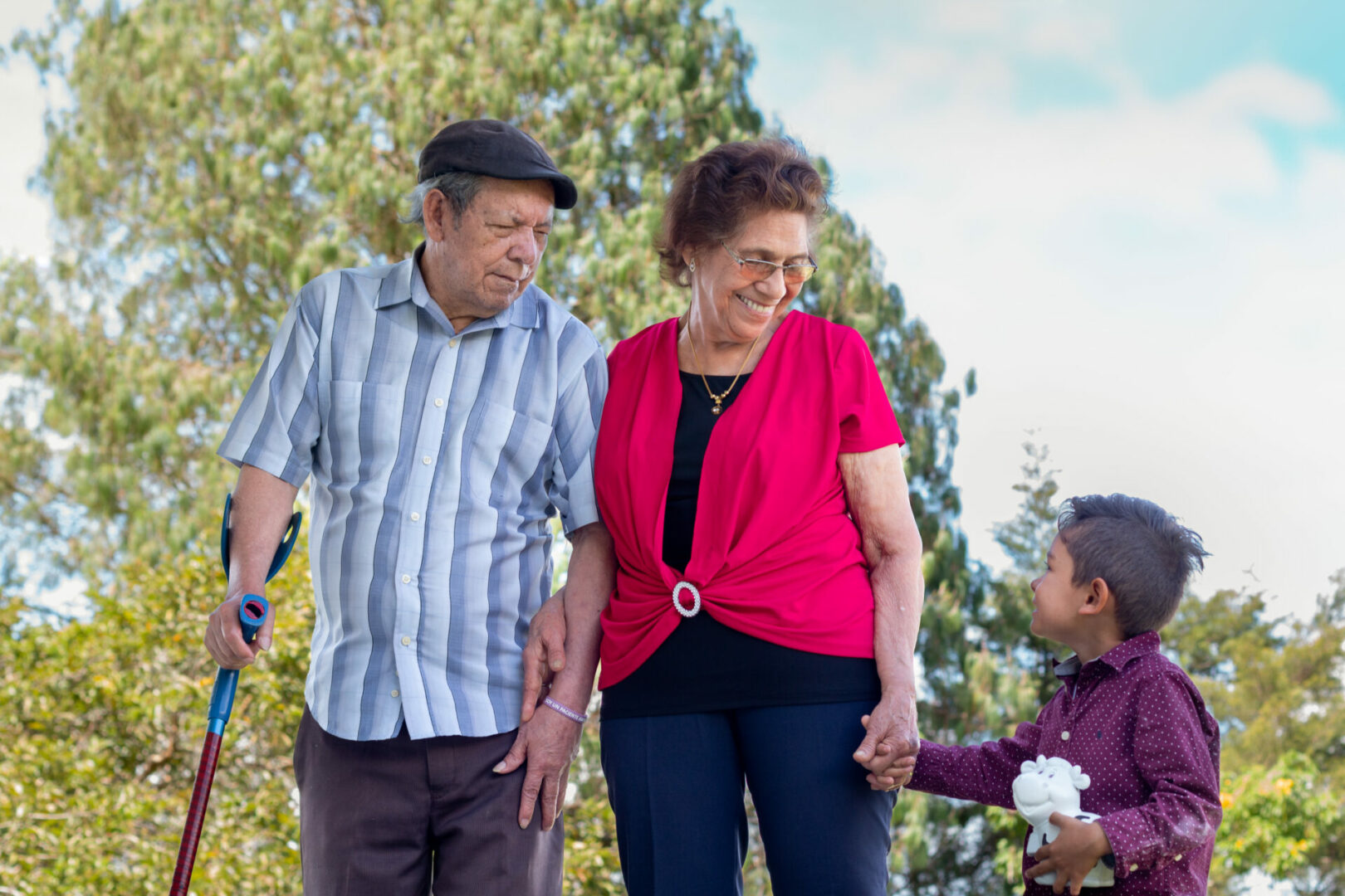 Happy elderly couple holding hands with their great grandchild.