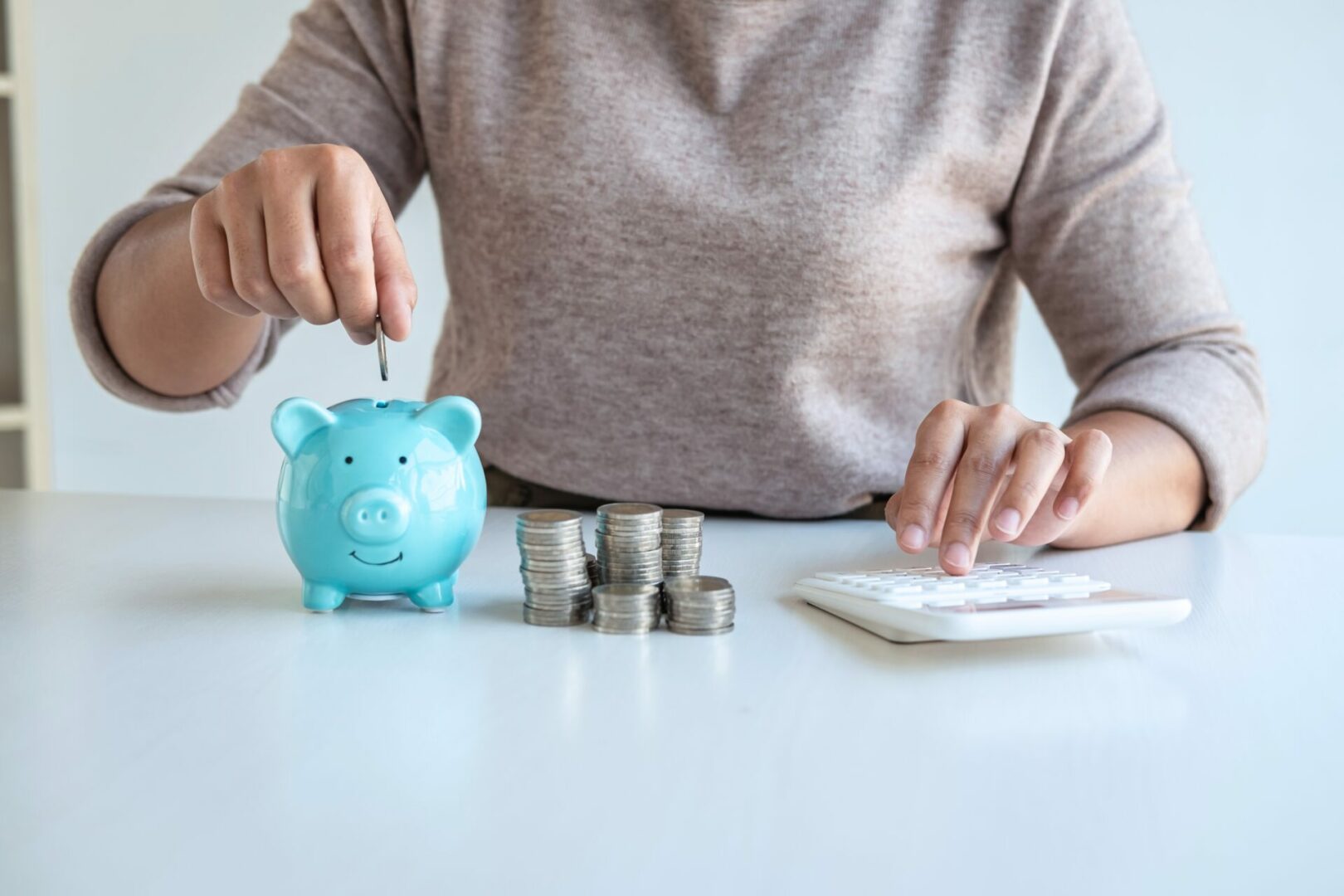 Young woman putting coins into piggy bank planning growing savin